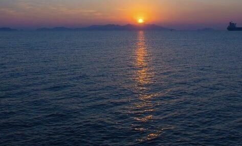 Sunrise over the ocean, waves reflecting golden light, symbolizing life’s beginnings and endings